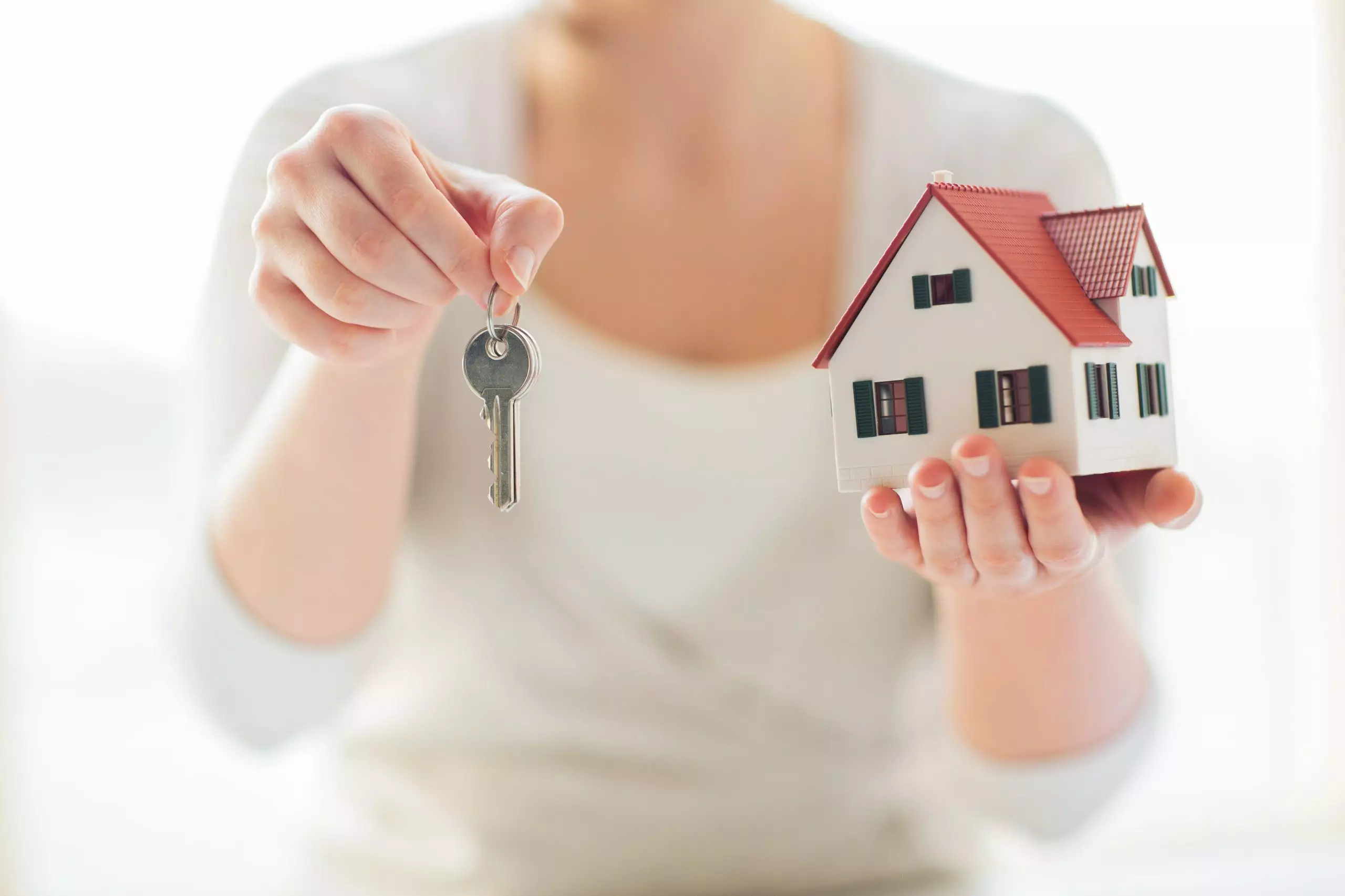 Building, mortgage, real estate and property concept - close up of hands holding house model and home keys